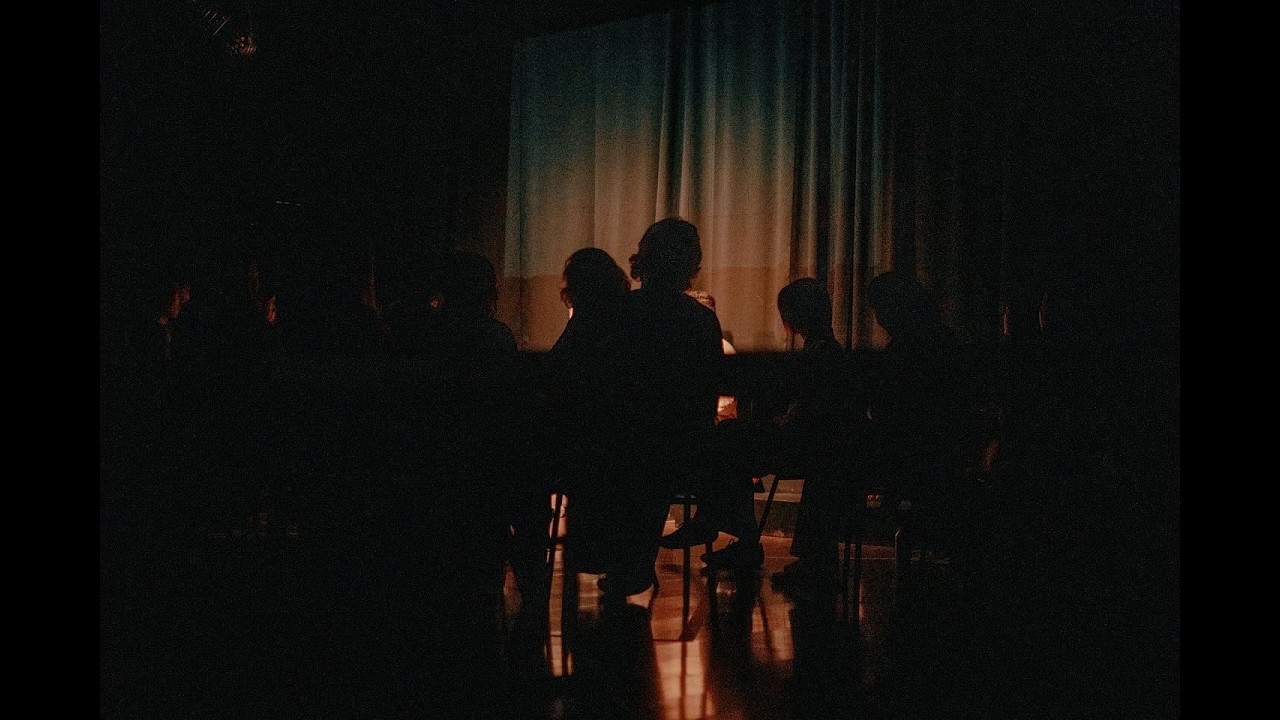 Participants gathered in a circle in a dimly lit room, from the Fragile Summer Camp trailer.