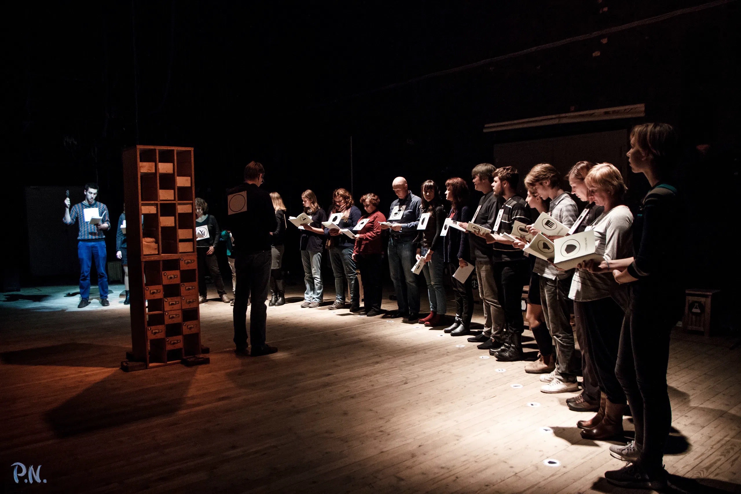 Participants holding illustrated performance scores in a semicircle on the stage of Listen City.