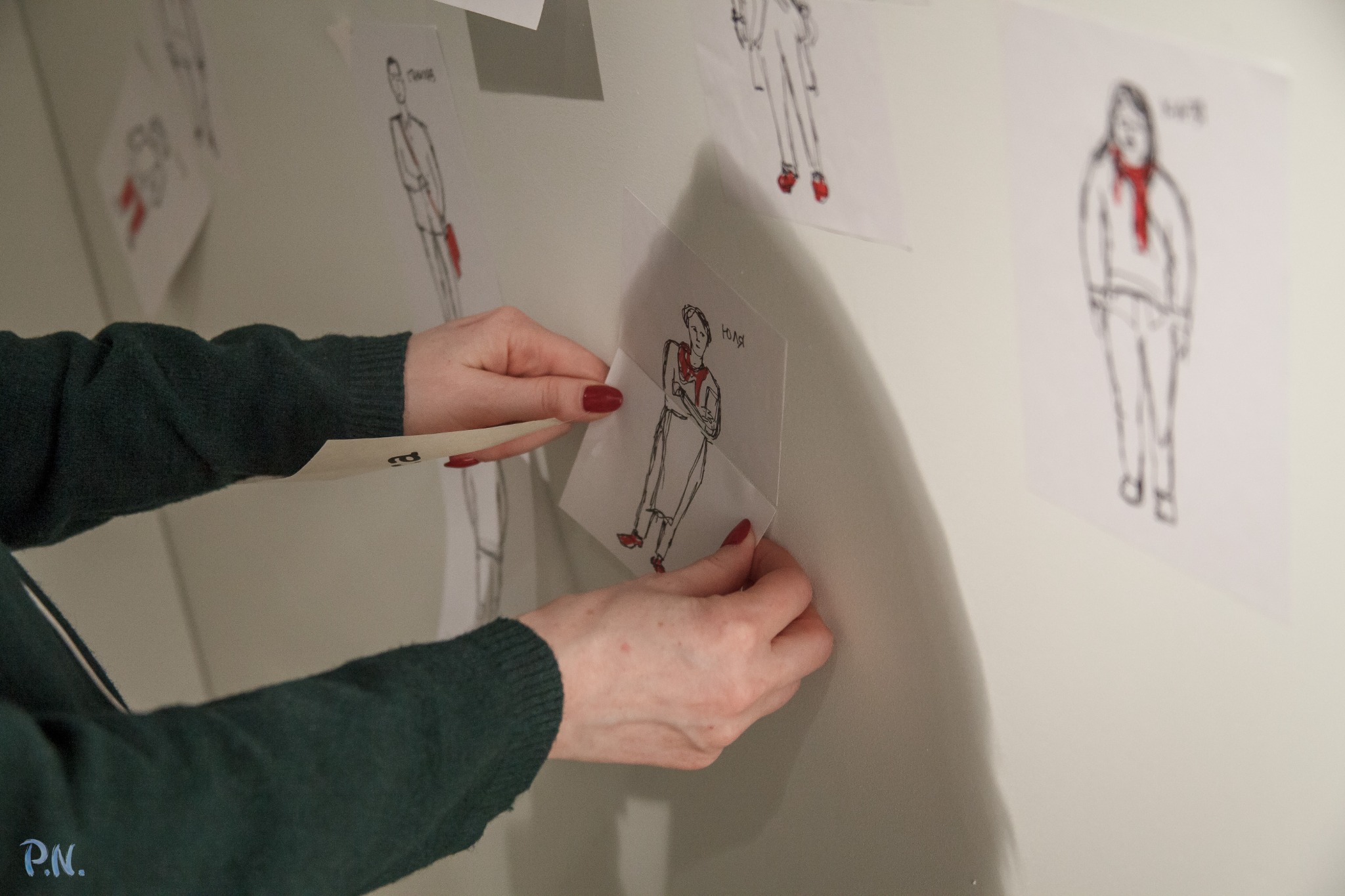 Hands arranging illustrated paper figures on a wall during Maria and Me.